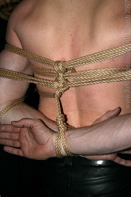 A close up of John's arms tied behind his back
