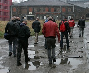 A group of leathermen walk around a crystal factory