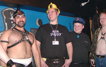 Four guys on stage wearing a fireman's hat, police hat, stethoscope and camoflage jacket