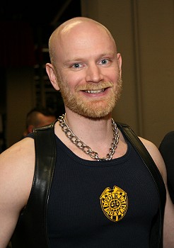 John wearing a navy blue ribbed t-shirt and black leather vest