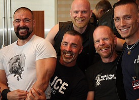 Five happy men in a tight group, grinning at the camera