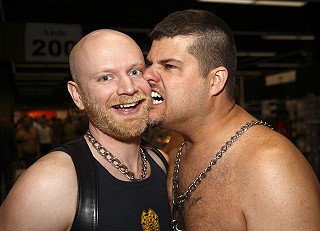 John smiling at the camera while the friend next to him playfully bites his cheek