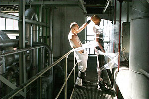 Two men playing in a industrial space, with transparent plastic wrap stretched around them
