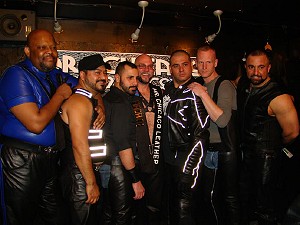 Seven leathermen stand together onstage with Chester in the middle