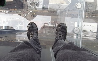 Looking down past John's shiny boots, through the glass floor to the ground 103 storeys below