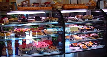 Several glass cabinets of colourful cakes and pastries - the kind you would see in any bakery