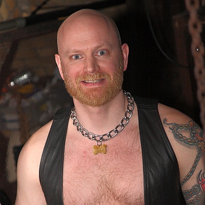 Picture of John in a leather vest at The Hoist, smiling at the camera